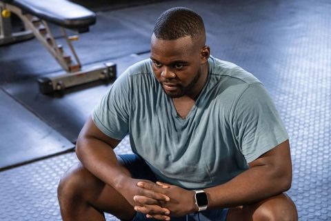 African american man resting between sets in gym, recovery, strength, focus