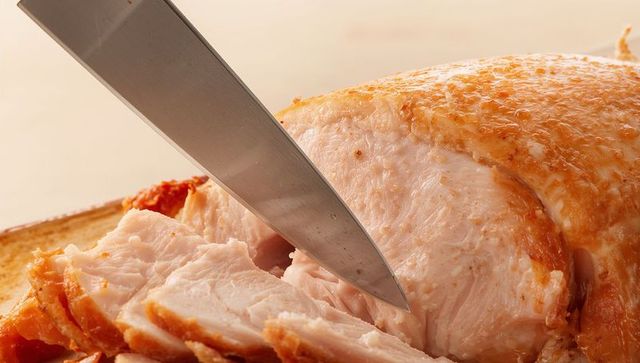 Slicing juicy roasted turkey breast with crispy golden skin for holiday feast
