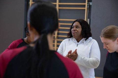 African american coach leading female team, clapping and motivating in gym