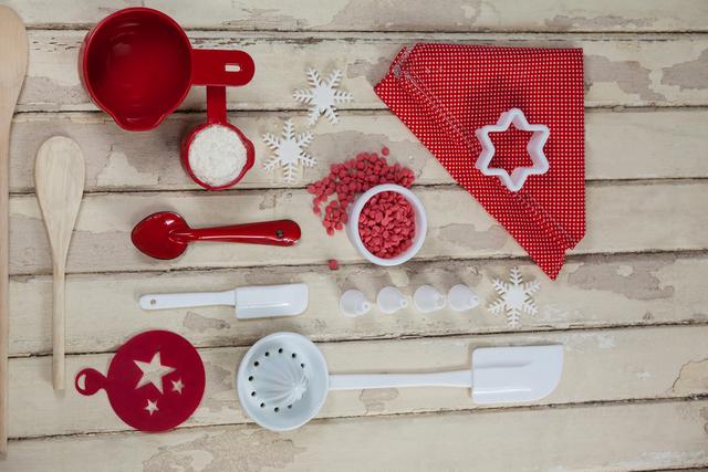 Spatula, spoons, icing sugar, dessert toppings and cookie cutter on wooden board