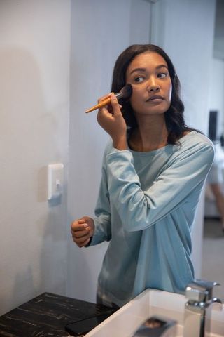 Woman applying makeup in modern bathroom reflecting self-care routine