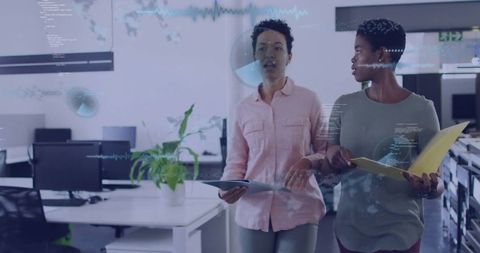 Businesswomen walking and discussing data in modern office