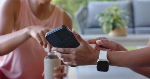 Using contactless card reader with smartwatch and reusable bottle on outdoor terrace