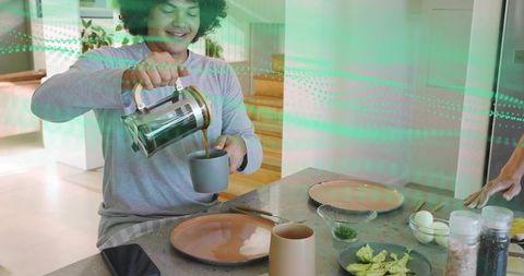 Man pouring french press coffee into mug at kitchen island, casual cozy modern breakfast