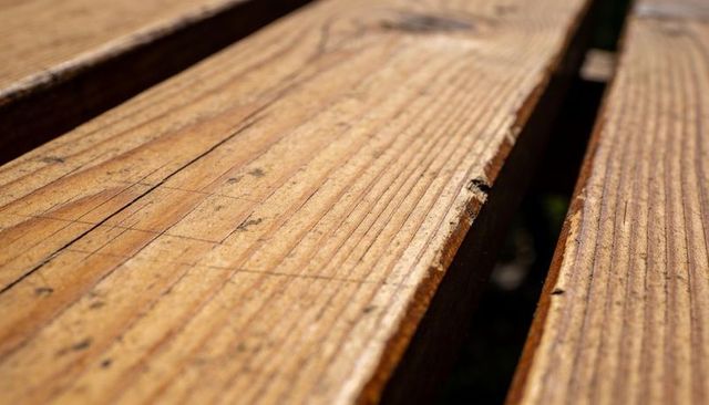 Sunlit Weathered Wood Planks Showing Grain, Scratches and Narrow Gap on Outdoor Deck Surface
