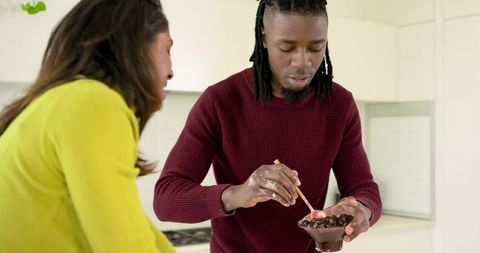 Diverse couple stirring berry dessert in bright minimalist kitchen