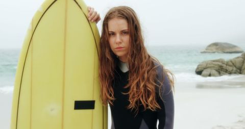 Caucasian Female Surfer on Beach with Yellow Surfboard