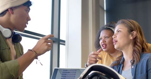 Multiracial team collaborating over laptop in bright coworking space brainstorming ideas
