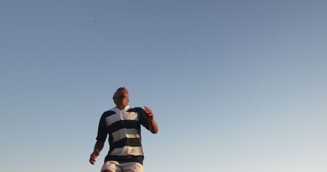 Man in striped rugby shirt looking upwards against clear sky - Download Free Stock Images Pikwizard.com