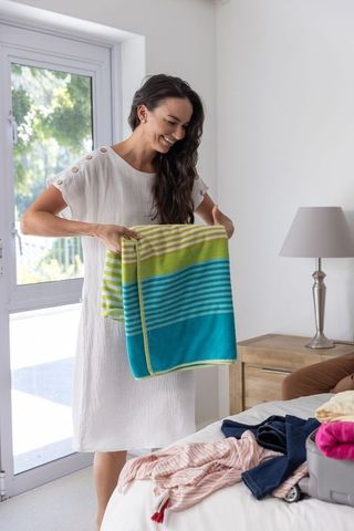 Woman Organizing in Bright Bedroom with Striped Towel