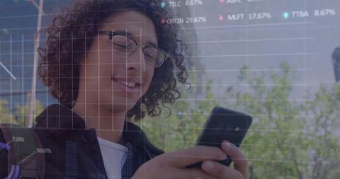 Young man using smartphone with financial charts overlay in urban plaza, fintech concept