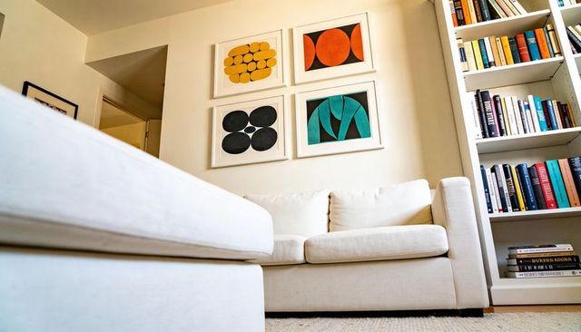 Cozy cream sofa with ottoman and built-in bookshelf featuring bold abstract framed art