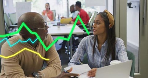 Senior and junior colleagues reviewing reports and discussing graphs in coworking office