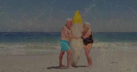 Holding surfboard, senior couple standing sunny beach turquoise trunks black swimsuit