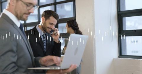 Smiling businessman talking on phone while coworker using laptop in open-plan office waveform