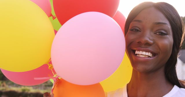 Smiling Woman Holding Colorful Balloons Outdoors at Sunset - Download Free Stock Images Pikwizard.com