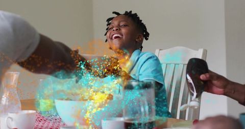 Laughing child enjoying syrup-topped breakfast with colorful glitter and family interaction