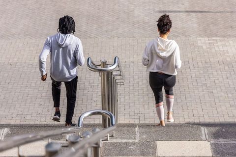 Friends walking down urban stone steps past stainless handrail and bike rack