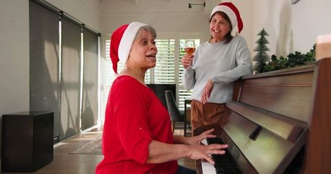 Senior Women Celebrating Christmas Around Piano With Wine