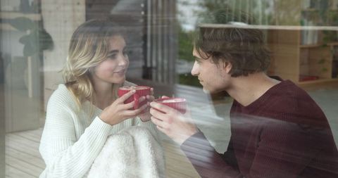 Cozy Couple Enjoying Blanketed Warmth Next to Window