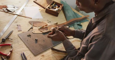 Skilled craftsman making leather belt in workshop
