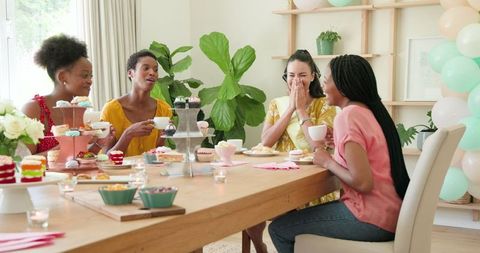 Diverse women enjoying afternoon tea party and desserts at home