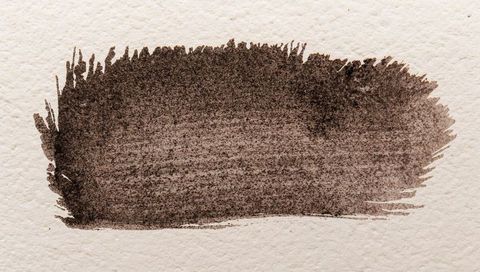 Dark brown watercolor brush stroke on cream textured paper with granular speckle