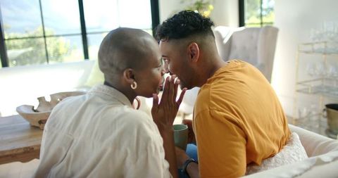 African american couple whispering on sofa in cozy modern living room, intimate moment