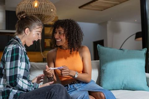 Diverse friends celebrating positive pregnancy at home
