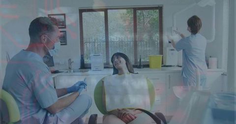Smiling patient receiving routine dental exam from masked dentist in modern clinic