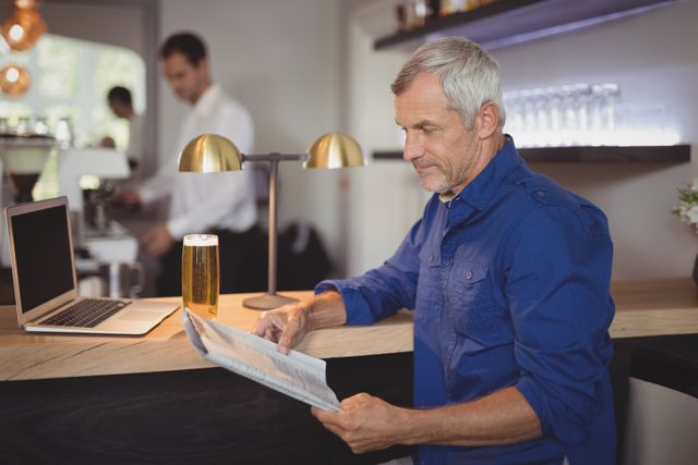 Mature man reading newspaper at counter in restaurant