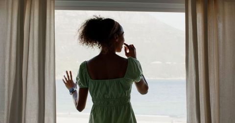 Woman Enjoying Ocean View from Window with Smartwatch