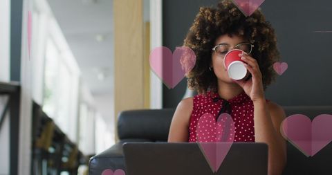 Biracial Woman Enjoying Coffee While Working on Laptop with Heart Overlays