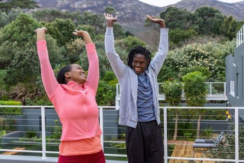 African american couple stretching on modern balcony with mountain view for outdoor fitness