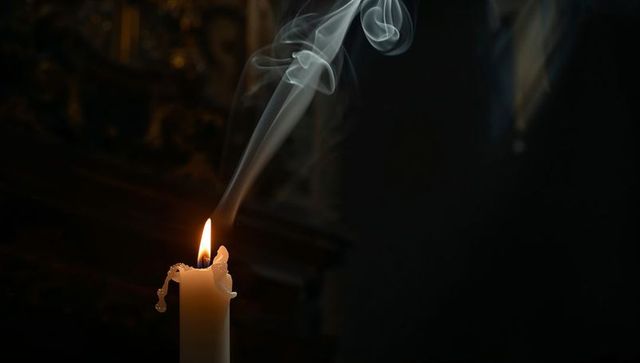 Moody chapel candle with flickering flame, curling smoke trails and dripping wax
