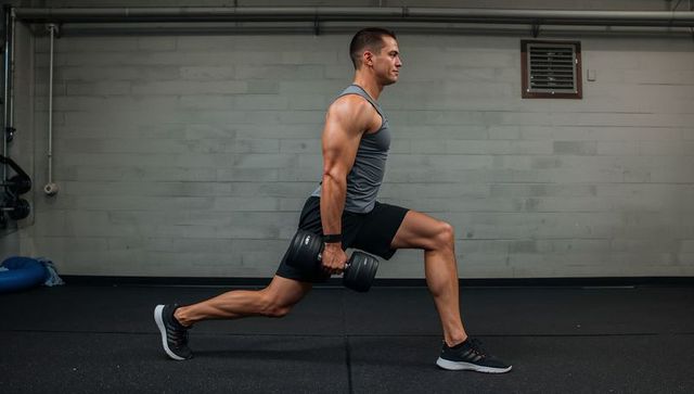Fit Man Performing Dumbbell Reverse Lunge in Industrial Gym, Strength Training Leg Workout