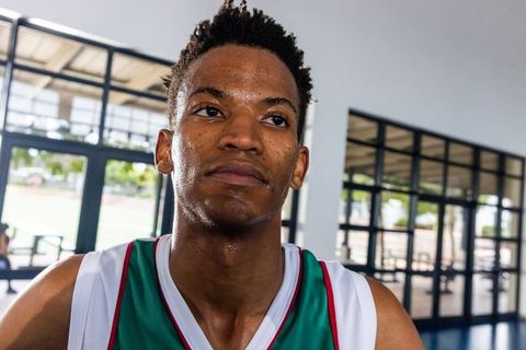 Confident Sweaty Basketball Player in Green-White Jersey at Gym Entrance