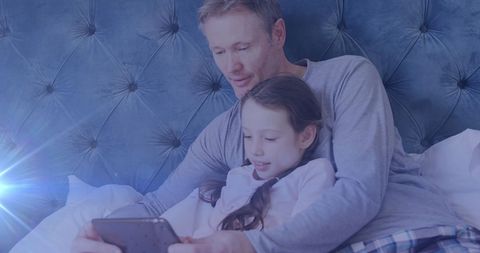 Father and Daughter Relaxing with Tablet in Bedroom