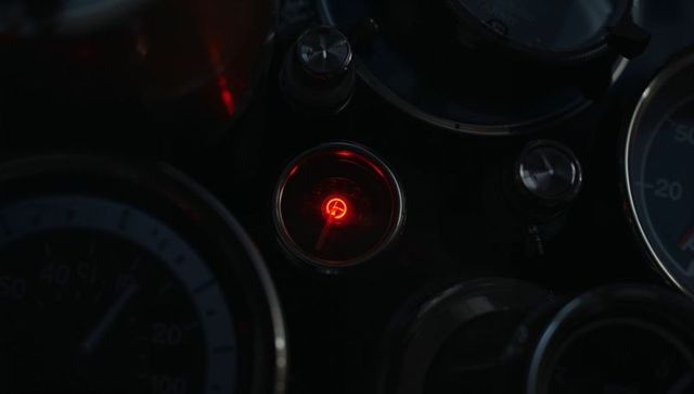Red warning light focal point among motorcycle gauges with chrome bezels and reflections