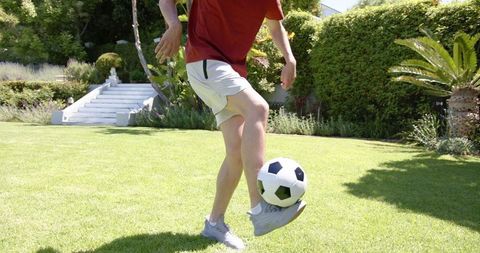 Young Male Practicing Soccer Skills in Sunny Garden