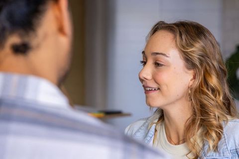 Woman smiling and talking with colleague in casual workspace during friendly collaboration