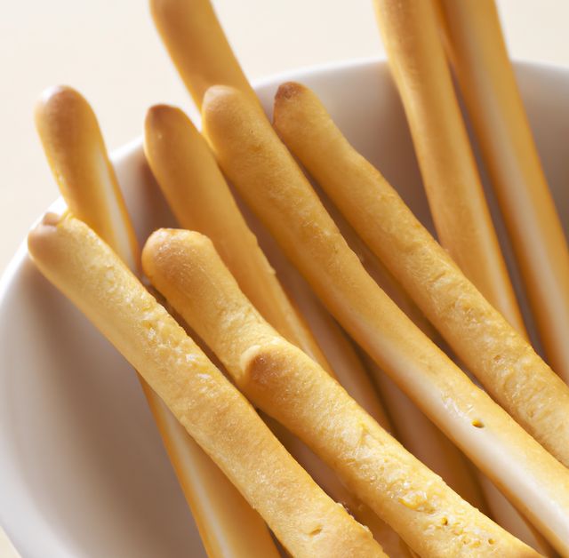 Close up of breadsticks in bowl on white background created using generative ai technology. Food and nutrition concept, digitally generated image.