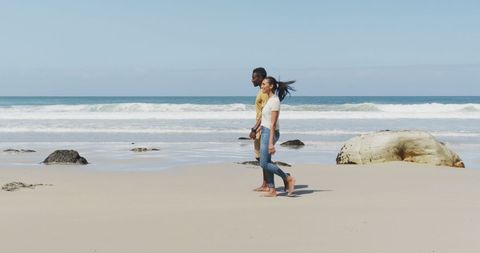 Couple Strolling on Sunlit Beach Hand in Hand - Download Free Stock Images Pikwizard.com