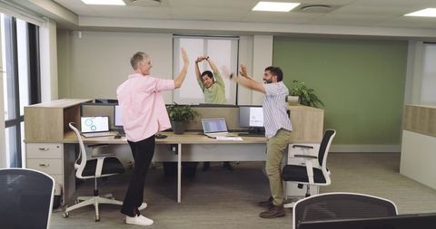 Energetic Team Celebrating Success with High-Fives at Work