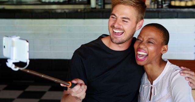 Happy couple taking selfie with selfie stick in coffee shop