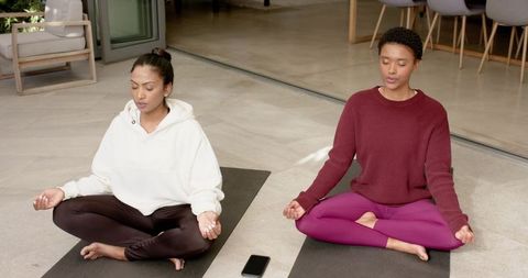 Two women meditating outdoors achieving mindfulness together