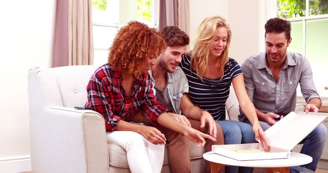 Young friends sitting together on couch in comfortable home. They are enjoying pizza and interacting. This image is great for campaigns focusing on friendship, social gatherings, home life, and leisure activities. Ideal for lifestyle blogs, social media, and advertising.