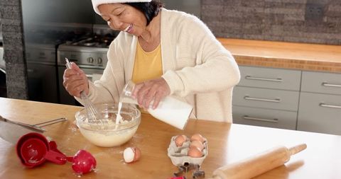 Senior woman joyfully baking in modern kitchen