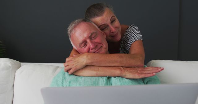 Happy caucasian senior couple embracing on sofa and talking. staying at home in isolation during quarantine lockdown.