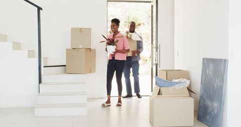 Joyful Couple Moving Into New Home Filling Entry with Boxes